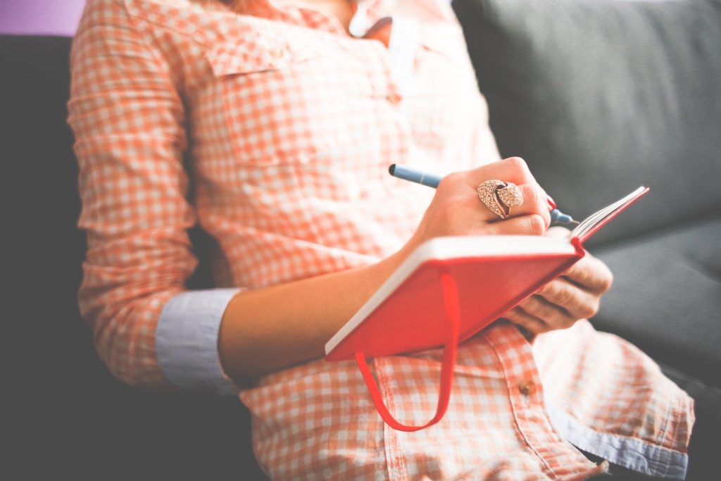 Woman writing in red notebook