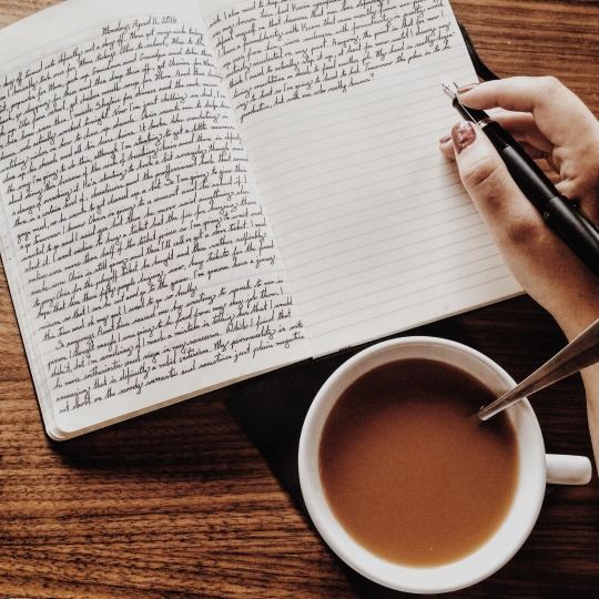 Writing in notebook with coffee