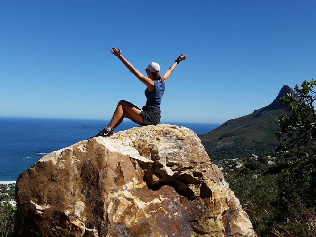 Woman sitting on top of mountain rock