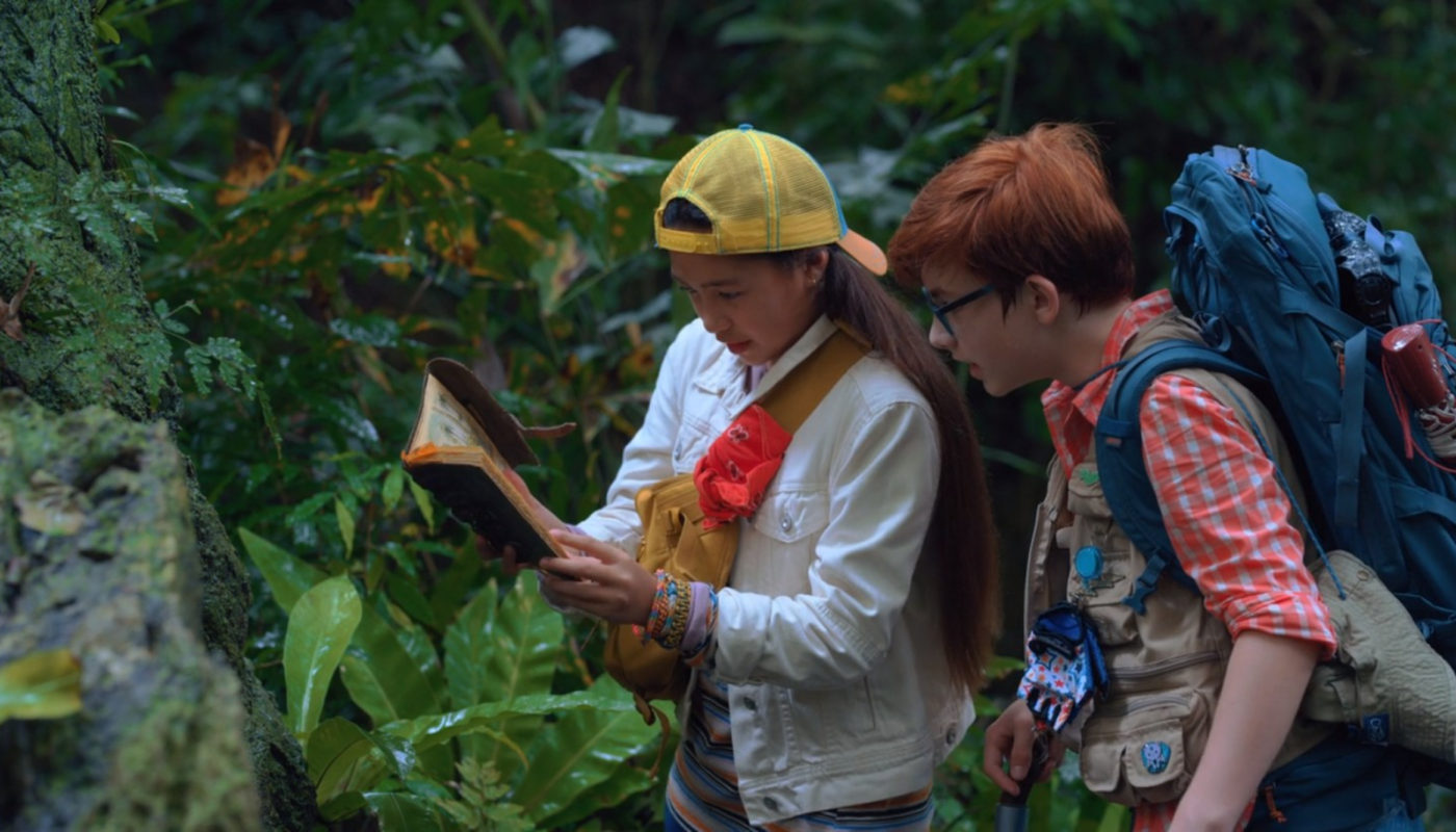 Finding 'Ohana Netflix Screenshot. Boy and girl looking at notebook in Hawaiian jungle.