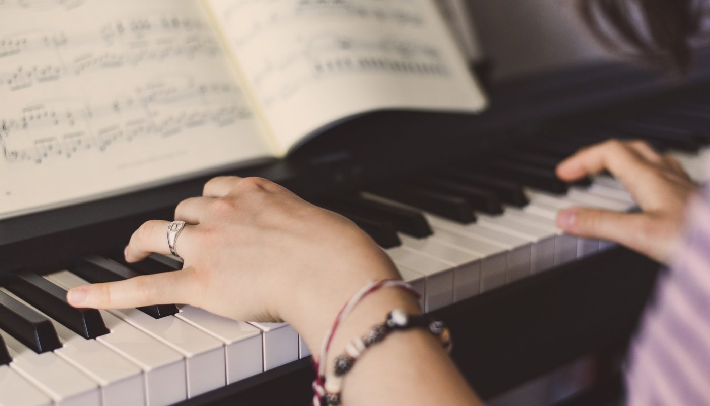 Woman's hands playing piano with sheet music