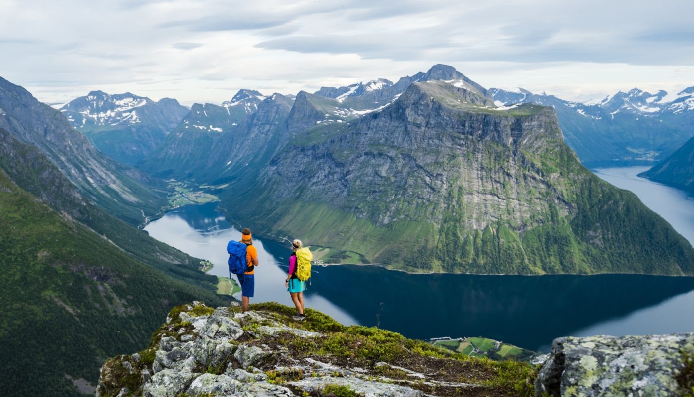 Couple hiking with Norway mountain and river in background