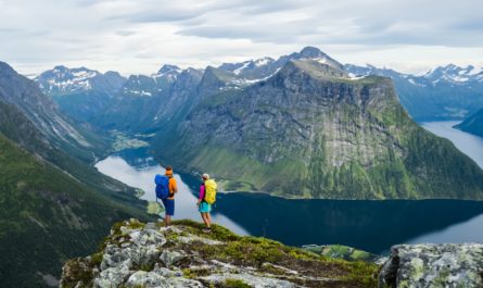 Couple hiking with Norway mountain and river in background