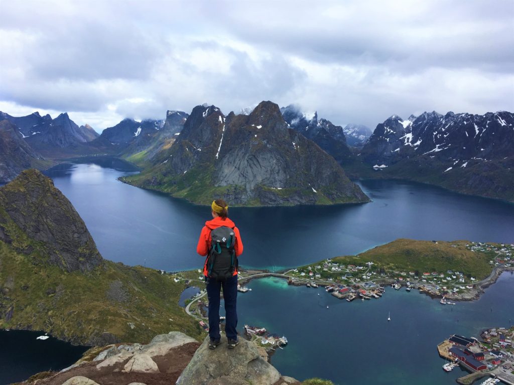 Woman with backpack looking down on Reinebringen from hiking