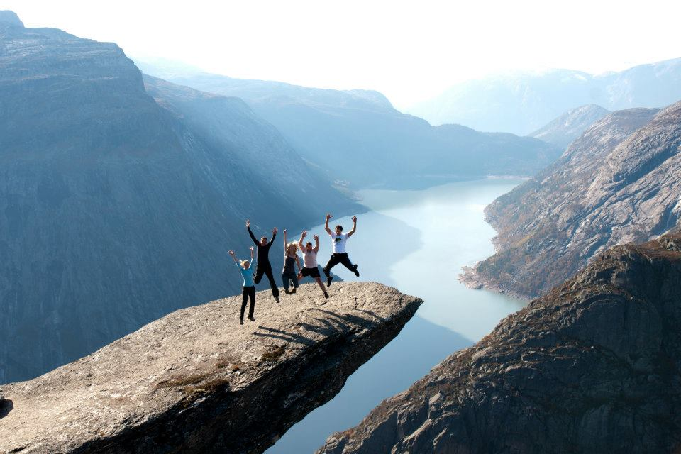 Hikers celebrating atop a rock outcrop at Trolltunga, Norway
