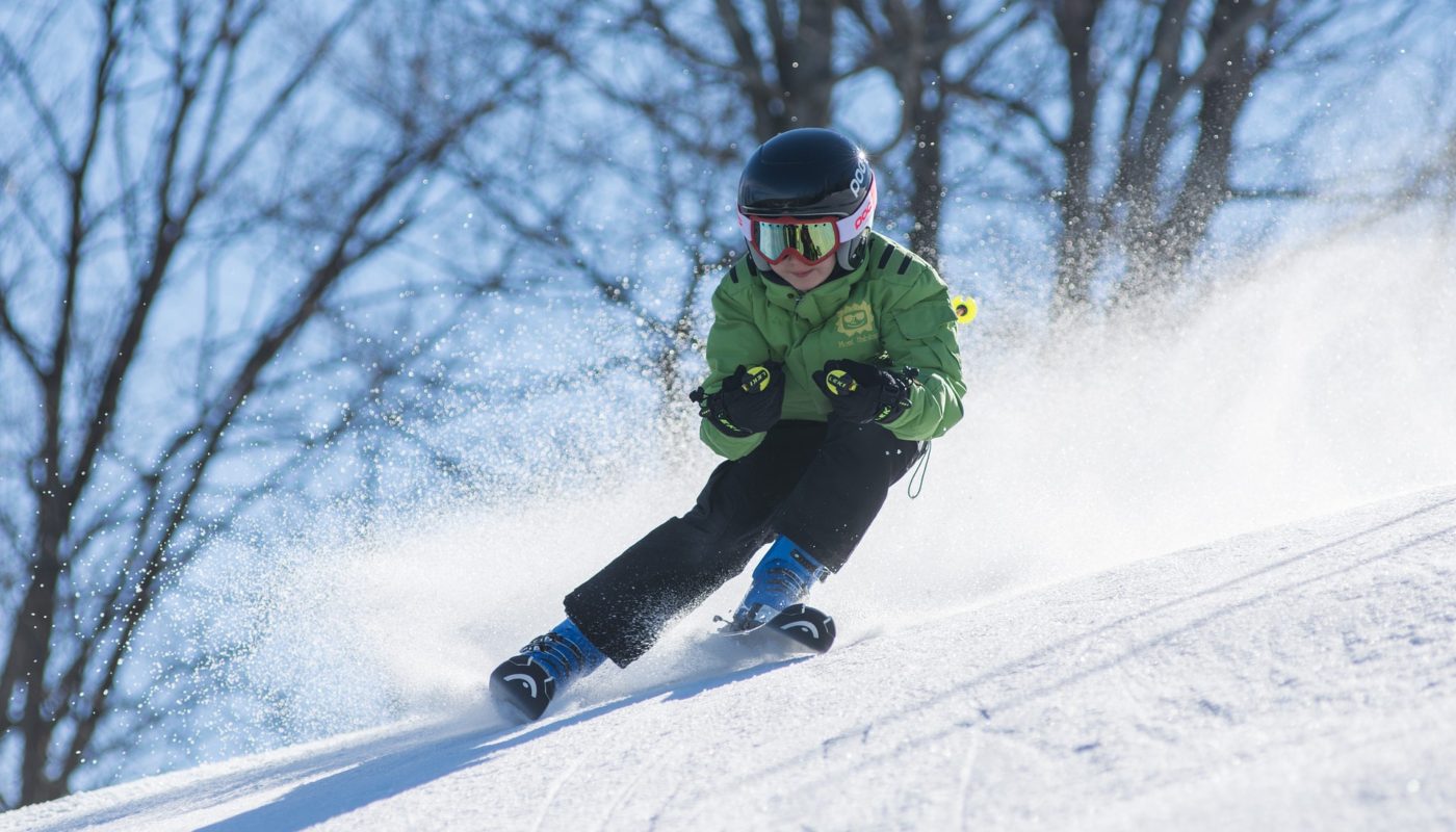 Young boy skiing, turning and throwing up snow