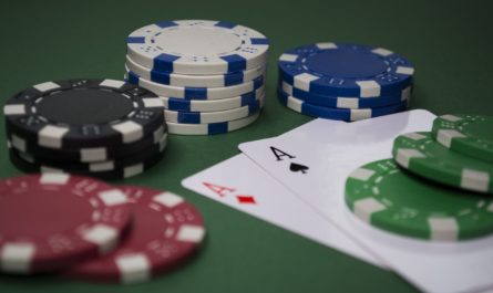 Poker chips and double aces on green tabletop