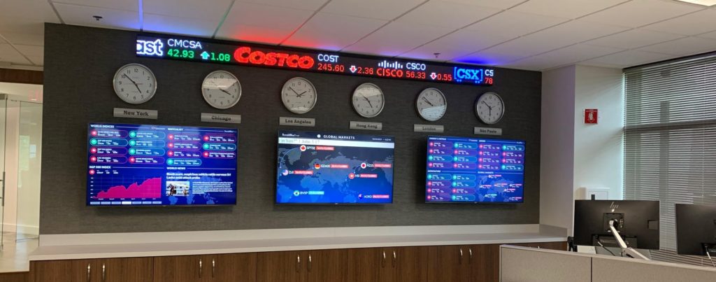 Stock monitors and time clocks on office wall