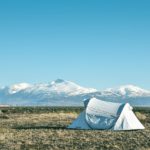 Lone white tent with snowy mountain in background